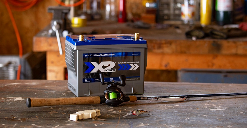 X2Power boat battery on a table with a fishing rod in front