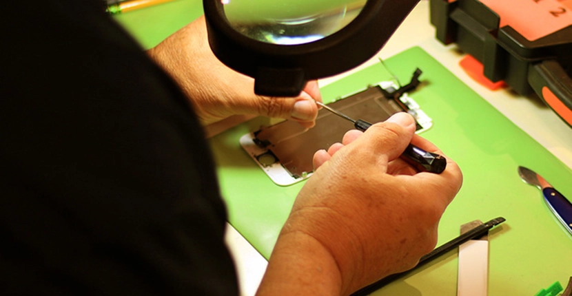 Working on a cell phone screen on a green mat
