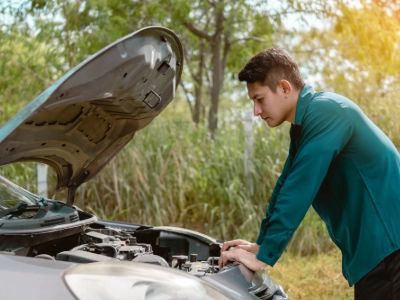 Man in green shirt looking at a car engine