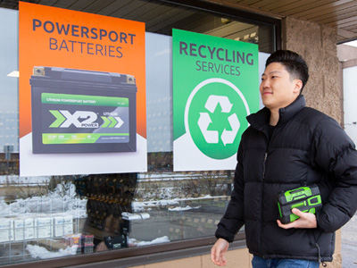 Person in a black coat caring a battery
