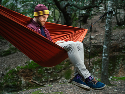 Guy sitting in a hammock in the woods