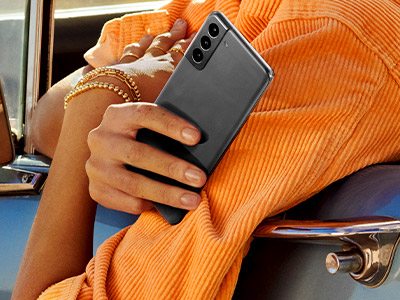 Hanging out a blue car window holding a phone