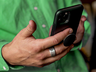 Person wearing green using a phone with a PopSocket