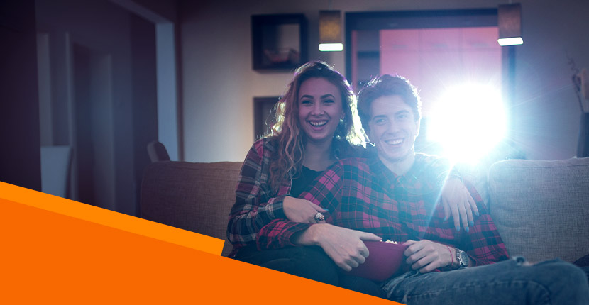 A couple sitting on the couch watching a movie